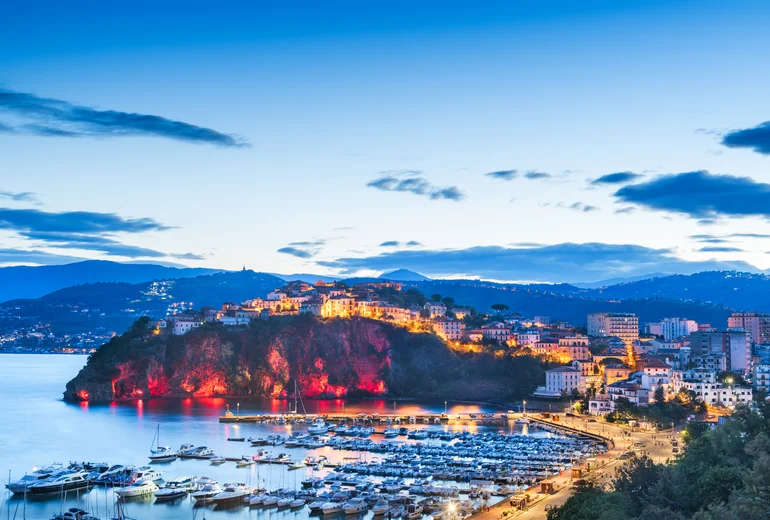 White-stone Italian town on a coastal cliff with turquoise sea below